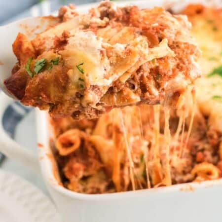 A slice of gluten free baked ziti is lifted from a casserole dish.