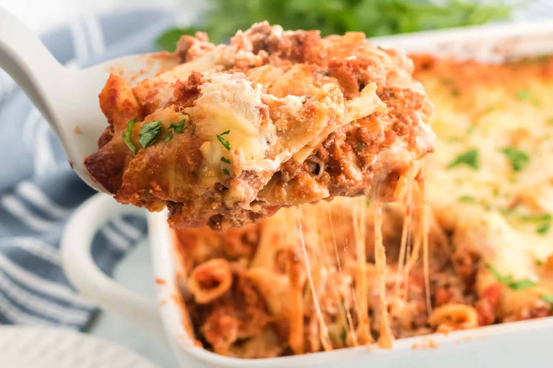 A slice of gluten free baked ziti is lifted from a casserole dish.