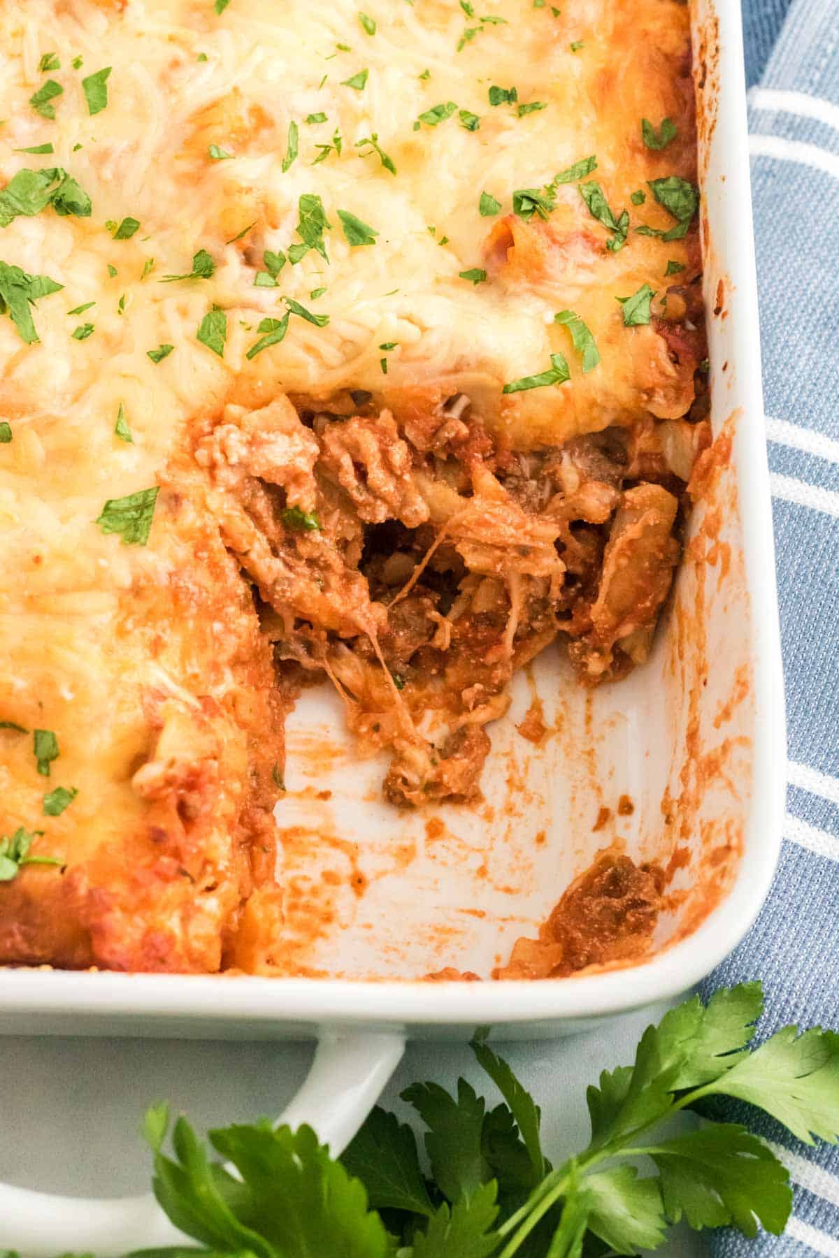 Baked ziti in a baking dish with a slice missing.