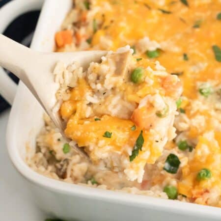 Chicken and rice is spooned out of a casserole dish.