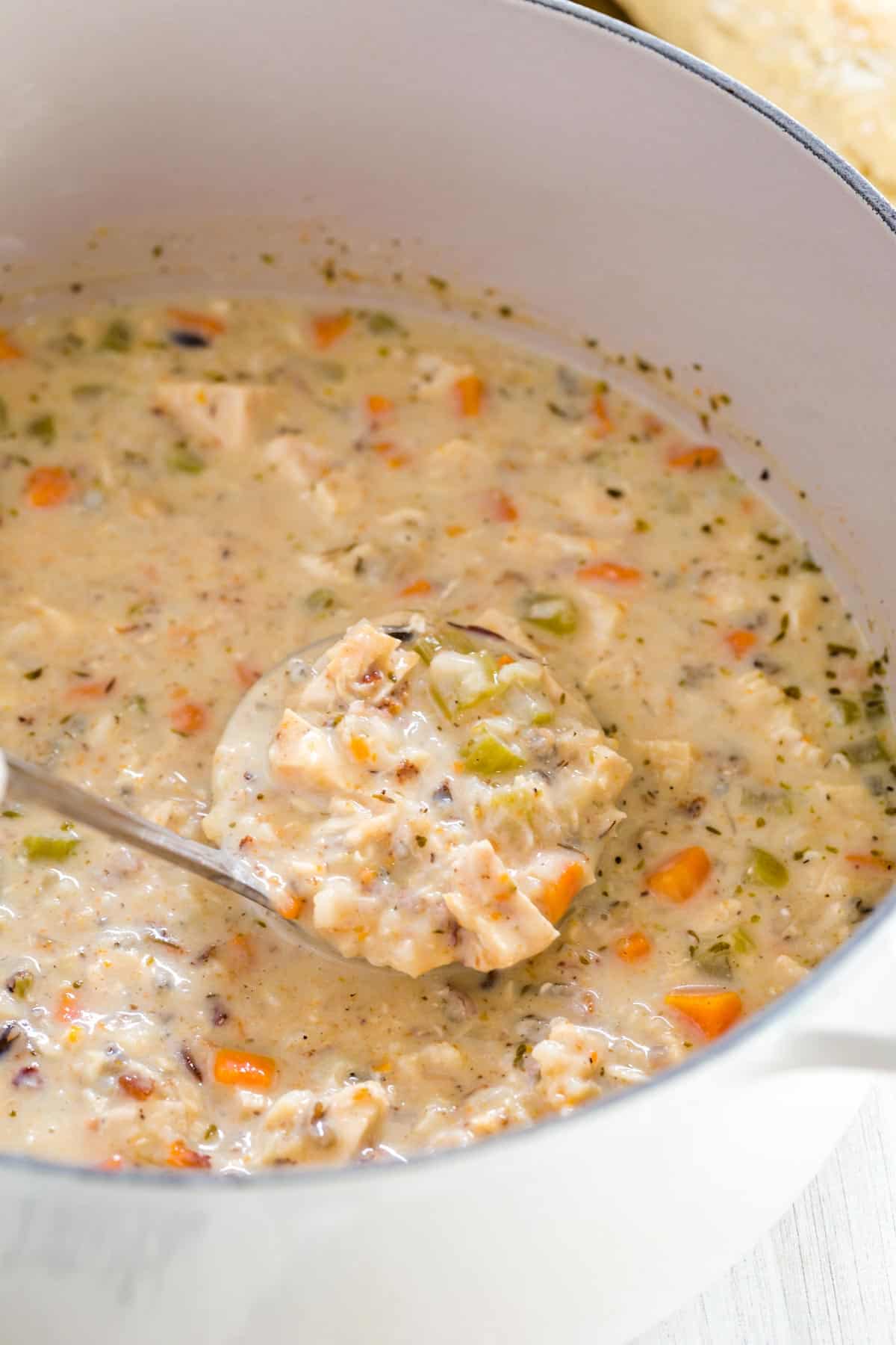 Creamy chicken wild rice soup is ladled from a pot.