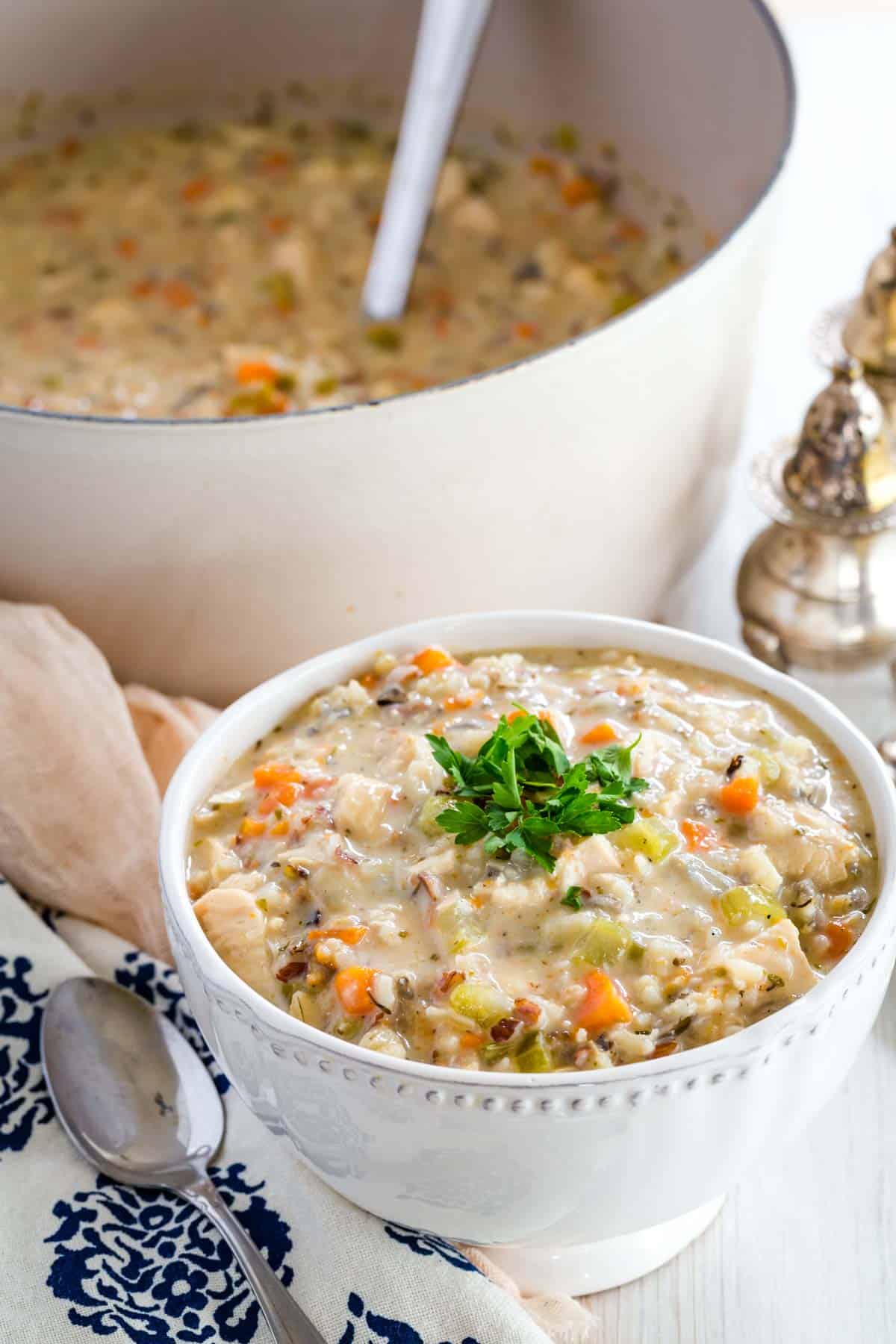 A bowl full of chicken wild rice soup with the pot in the background.