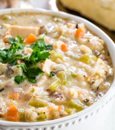 A bowl full of chicken wild rice soup garnished with fresh parsley.