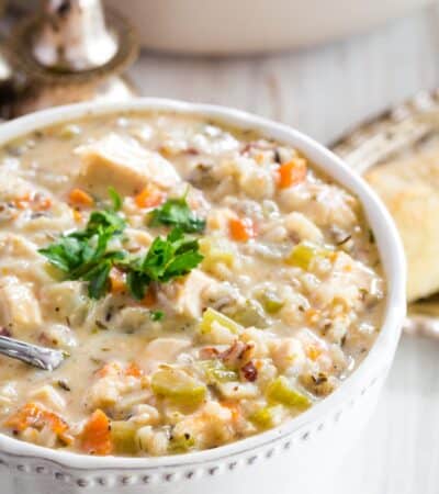 A bowl full of chicken wild rice soup garnished with fresh parsley.