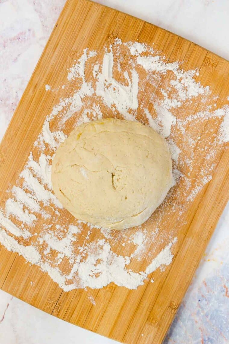 A ball of dough on a flour-dusted cutting board.