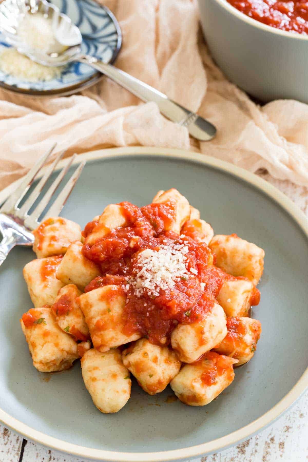 Gluten-free gnocchi served with tomato sauce and parmesan on a plate.
