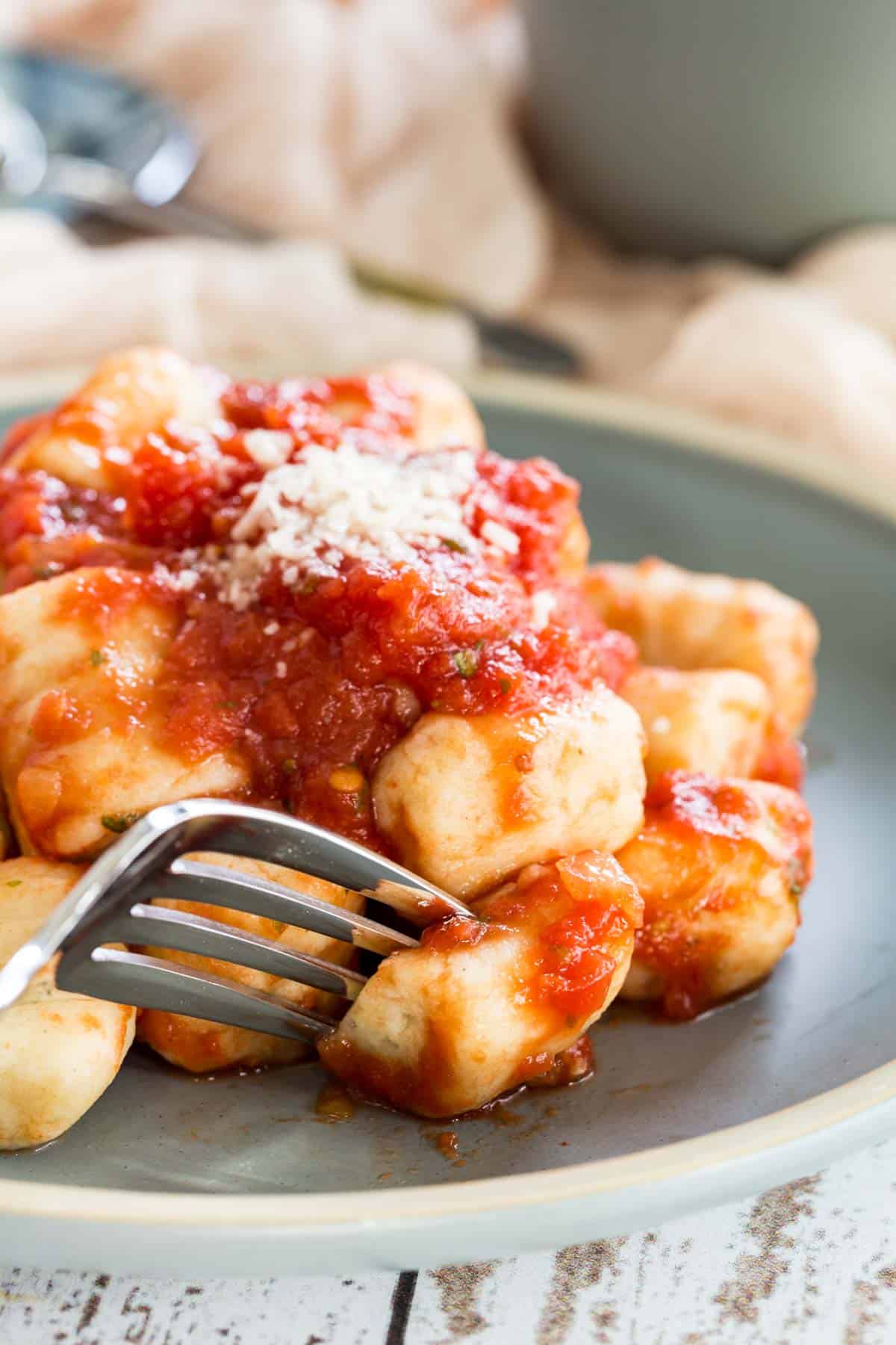 Gnocchi in tomato sauce on a plate, with a fork.