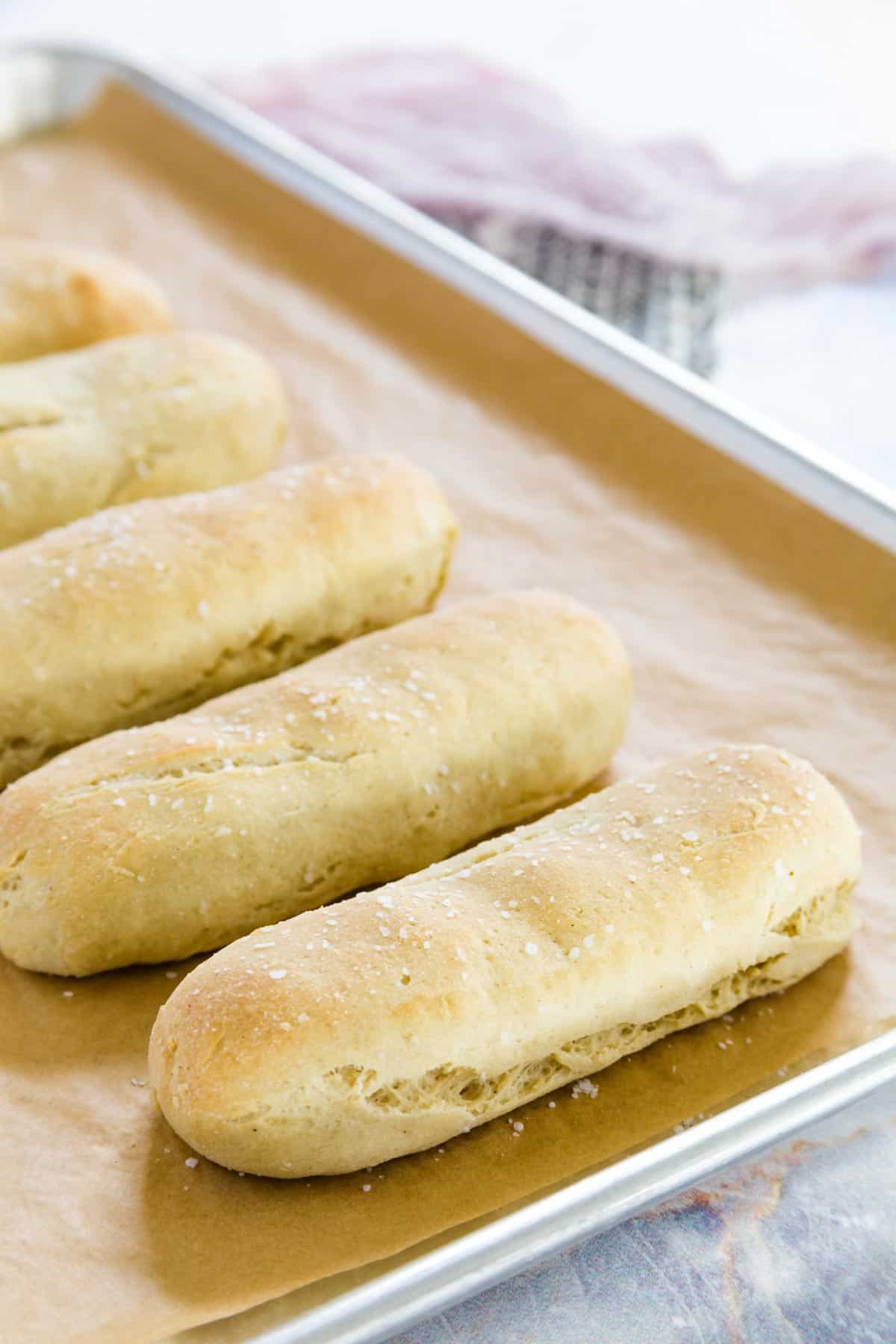 Baked breadsticks arranged in a row on a baking tray.
