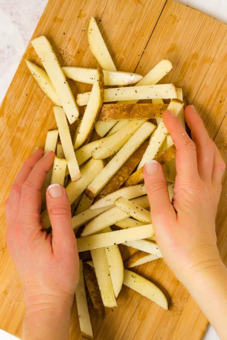 tossing uncooked fries together to coat with salt and pepper