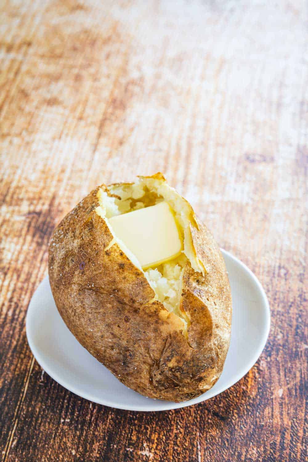 a crispy baked potato sliced open with butter inside