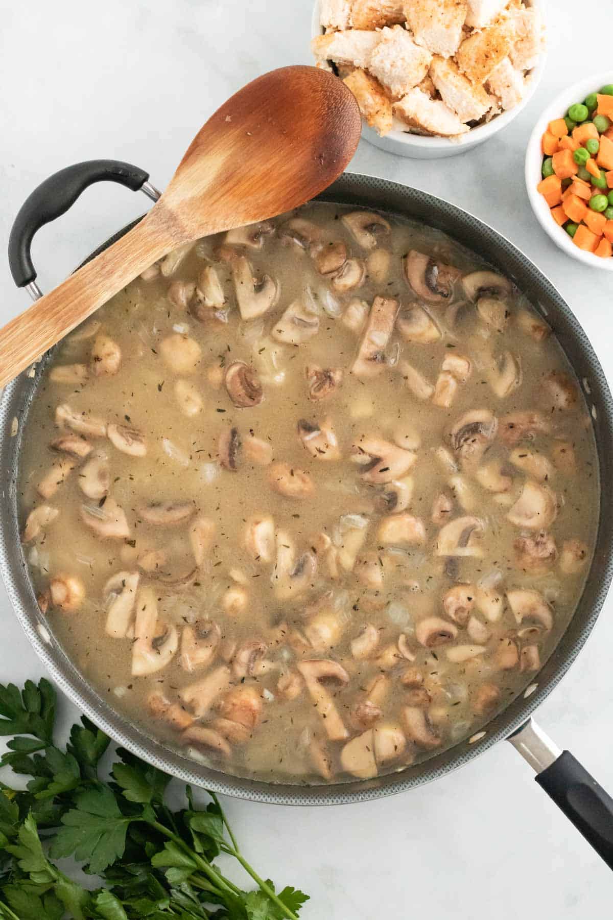Rice and chicken broth is added to a skillet with mushrooms.