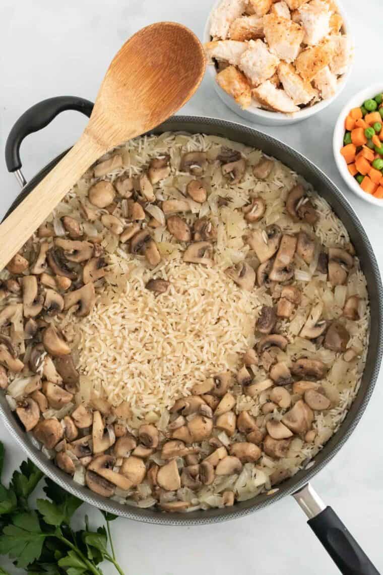 Rice and sautéed mushrooms simmer in chicken broth.