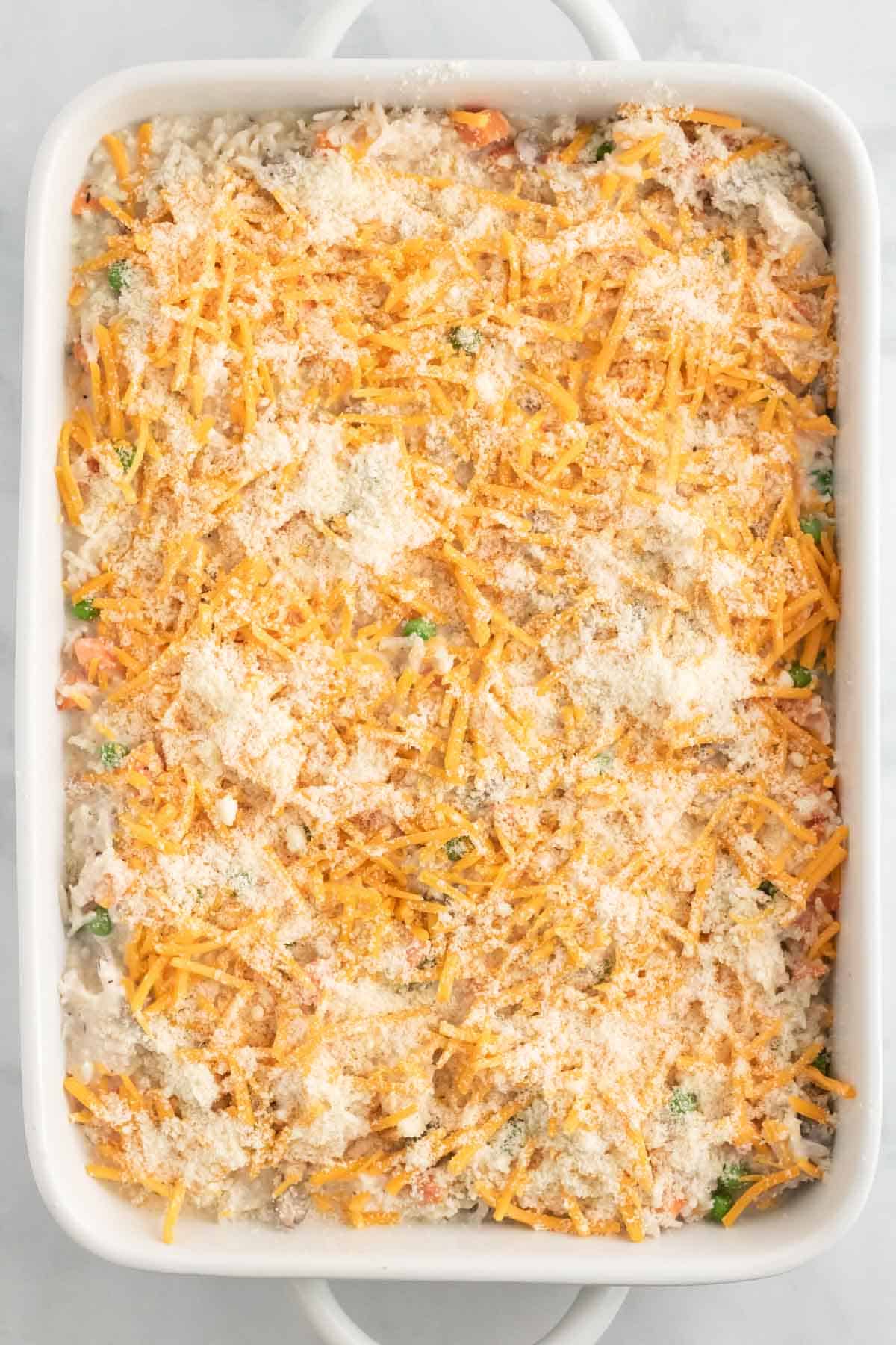 Creamy chicken and rice in a casserole dish is topped with shredded cheese.