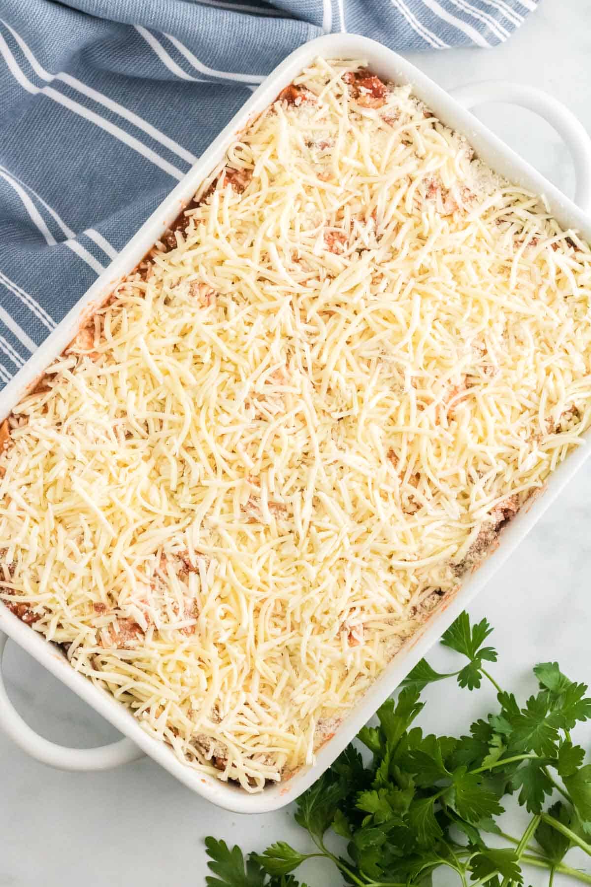 Unbaked ziti pasta casserole topped with shredded mozzarella cheese.