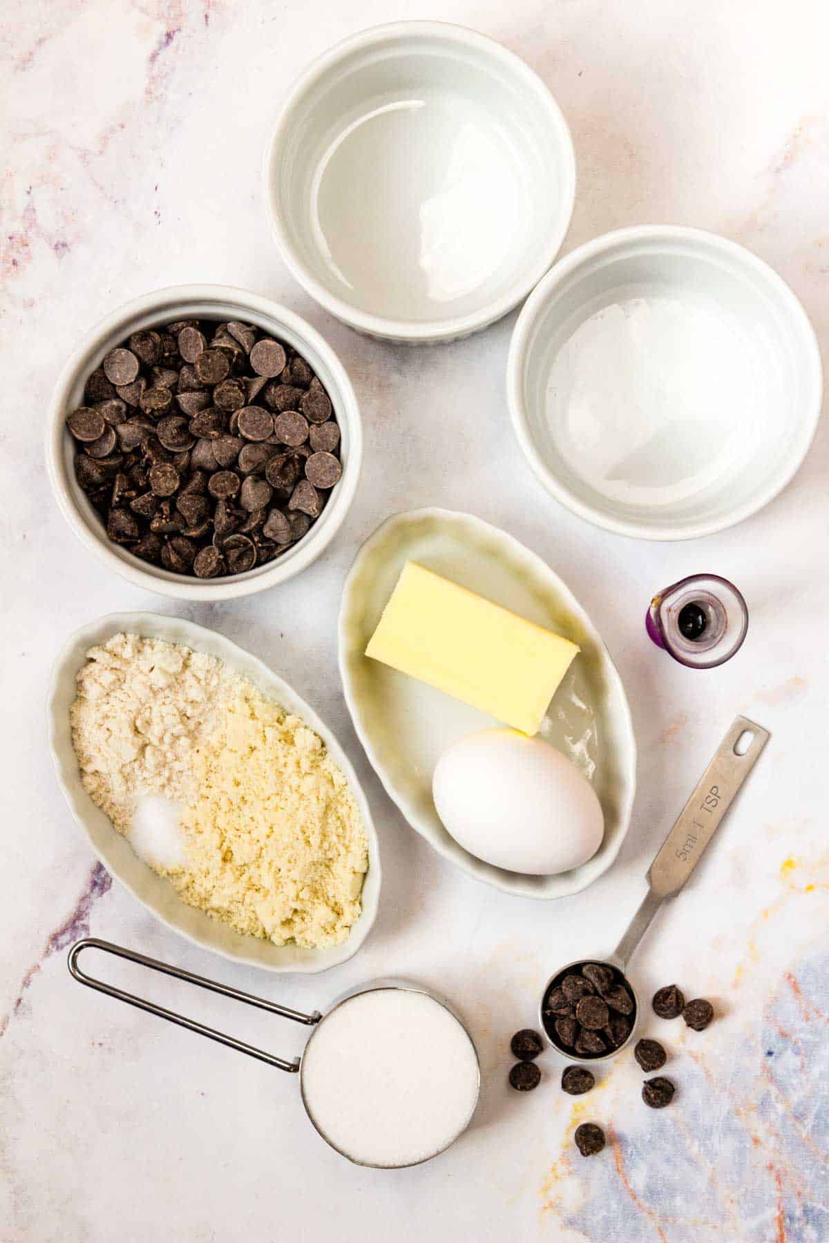 Two empty ramekins and all of the ingredients to make mug brownies.