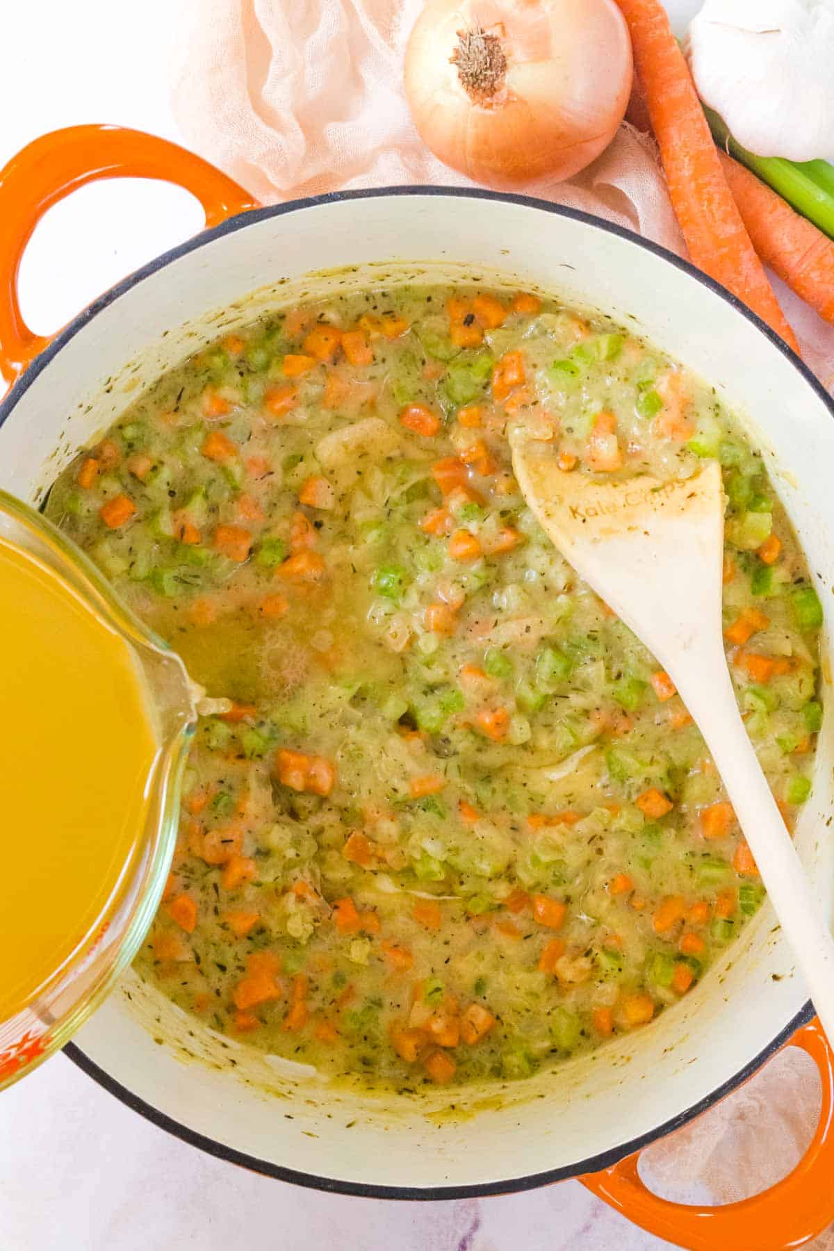 Chicken broth is added into the pot with sauted vegetables.