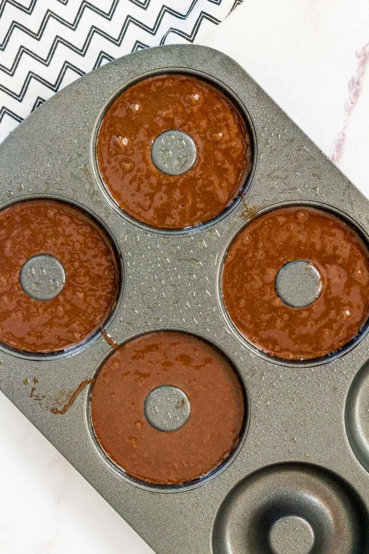 A donut tray is filled with chocolate donut batter.