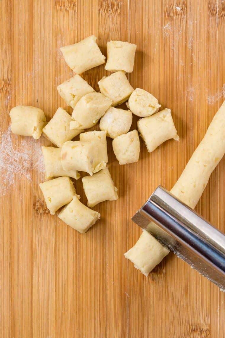 A pastry cutter is used to cut ropes of dough into small gnocchi shapes.