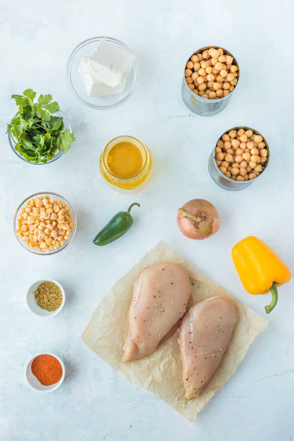 chicken breasts, cans of chickpeas, and other ingredients to make instant pot white chicken chili on a countertop