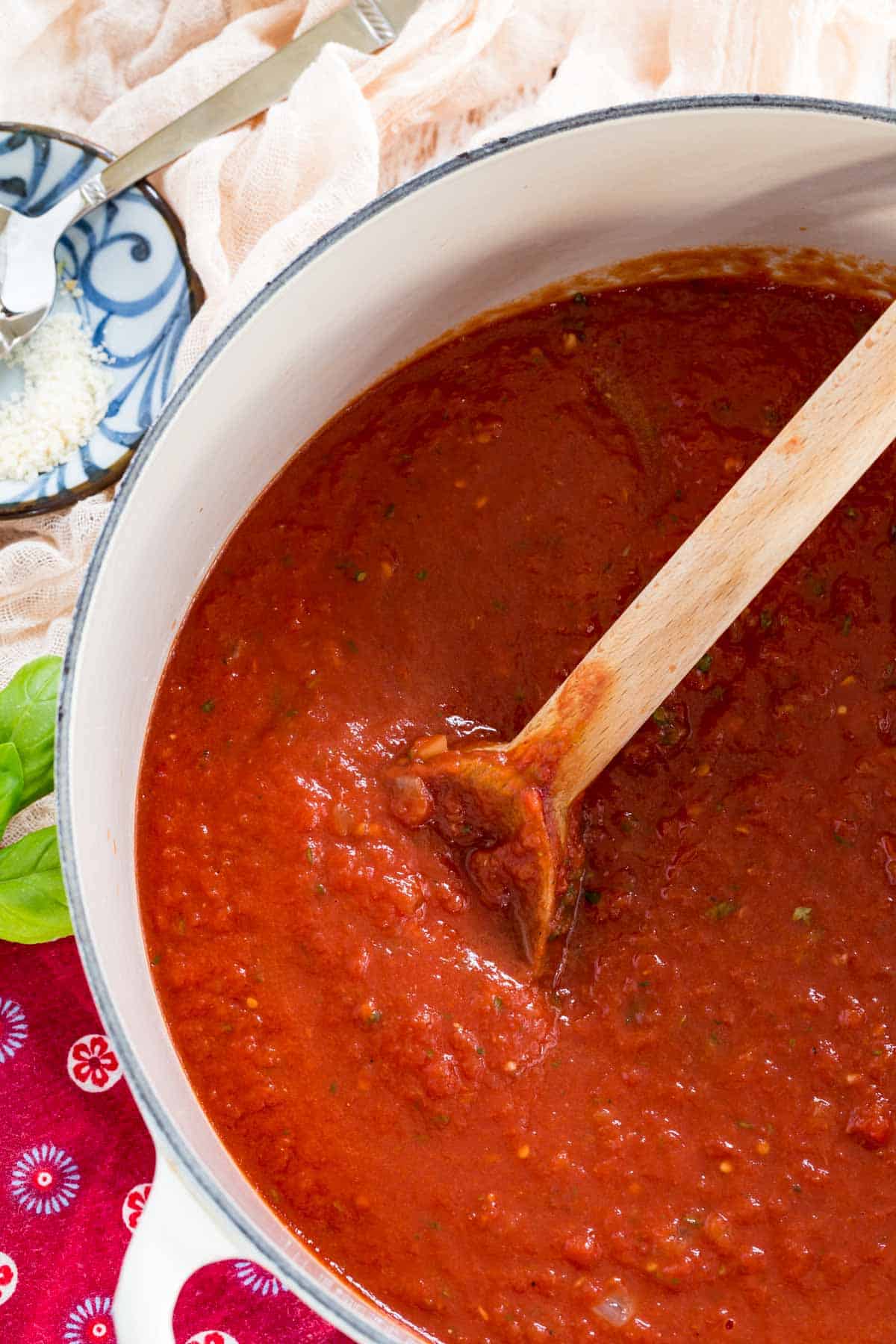 A wooden spoon is used to stir homemade marinara sauce.