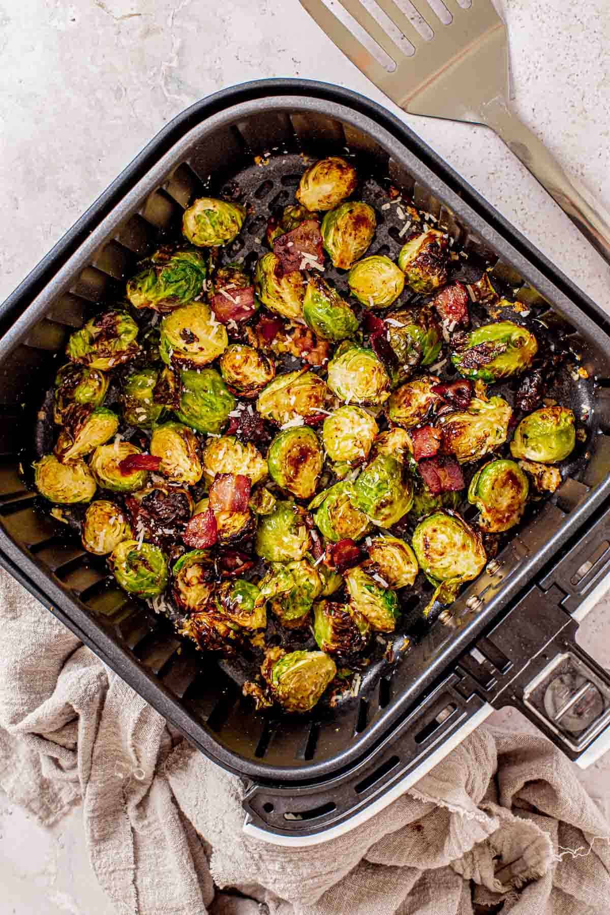 Brussels sprouts sprinkled with bacon and parmesan cheese in an air fryer