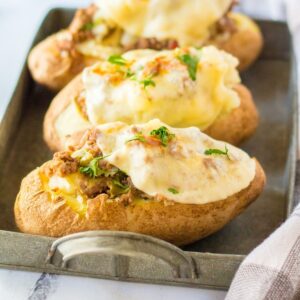 Three Philly Cheesesteak Baked Potatoes on a metal serving tray.