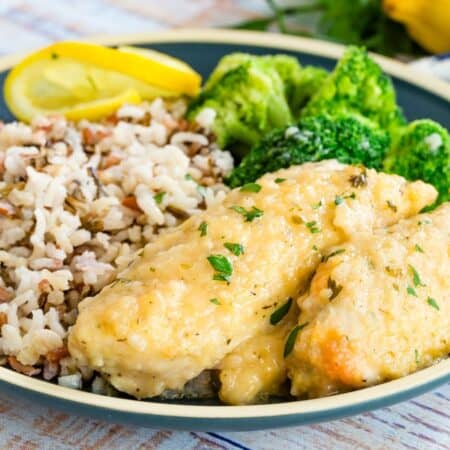 chicken tenders with lemon sauce on a plate with rice and broccoli