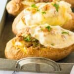 Stuffed baked potatoes on a serving tray with cheese melted on top.