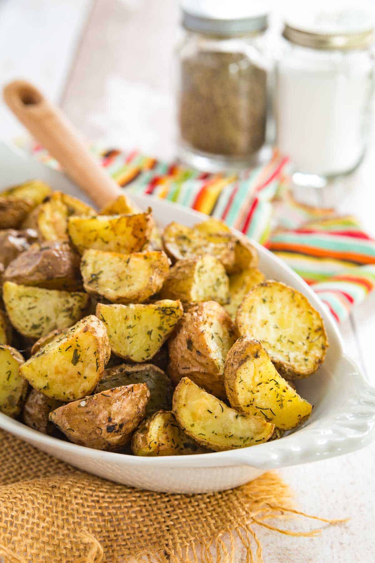 A dish filled with crispy air fryer ranch potatoes, with a spoon for serving.