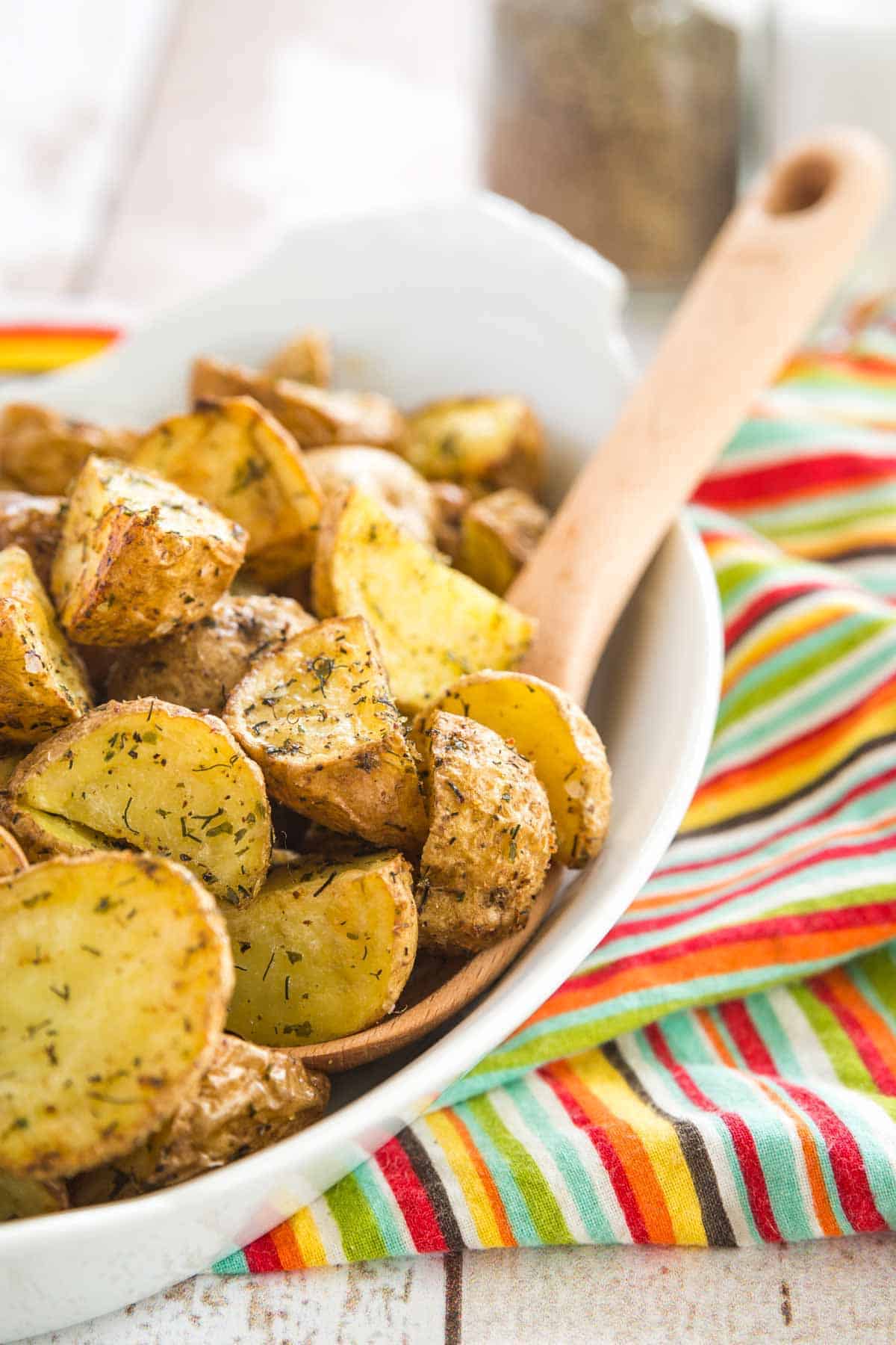 A dish filled with crispy air fryer ranch potatoes, with a spoon for serving.
