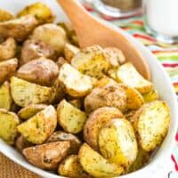 A dish filled with crispy air fryer ranch potatoes, with a spoon for serving.