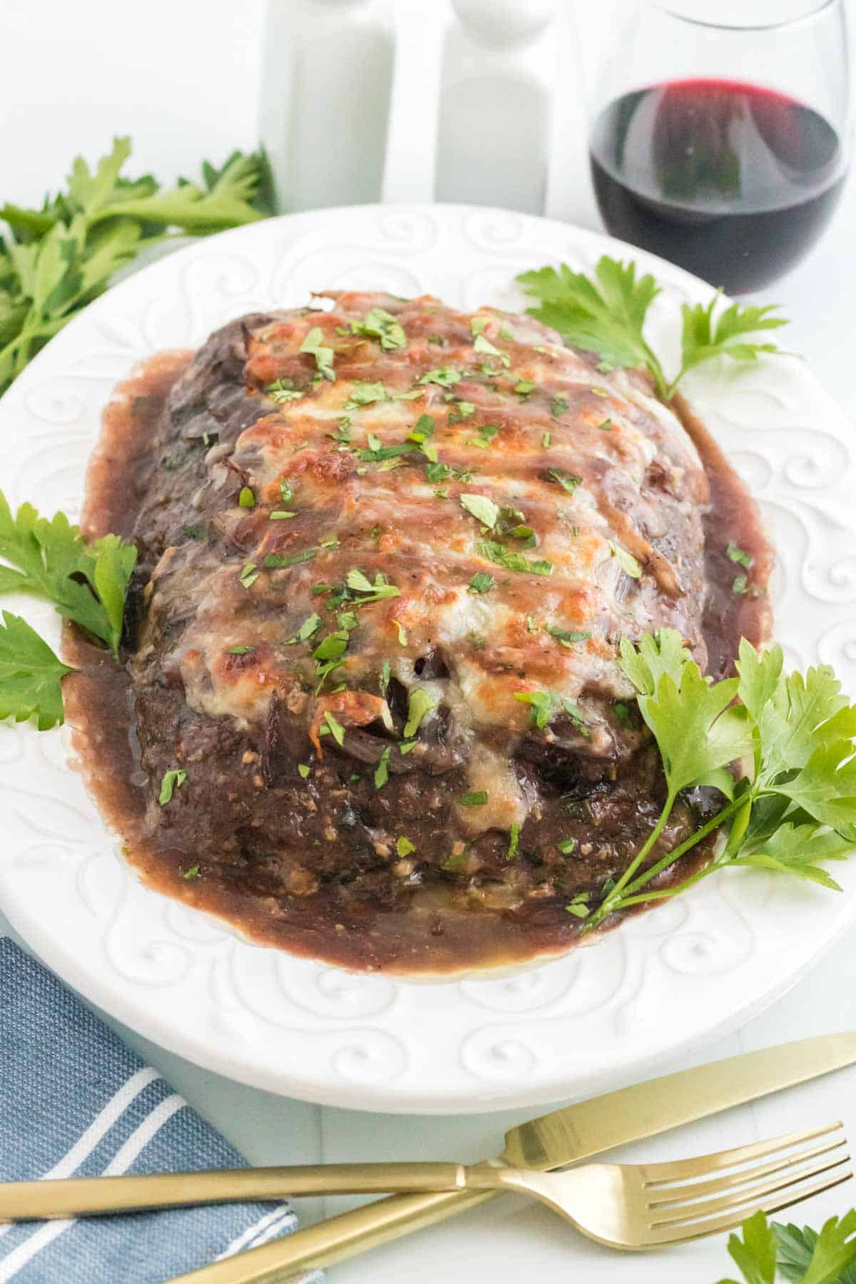 Meatloaf on a large serving platter with a glass of red wine behind it