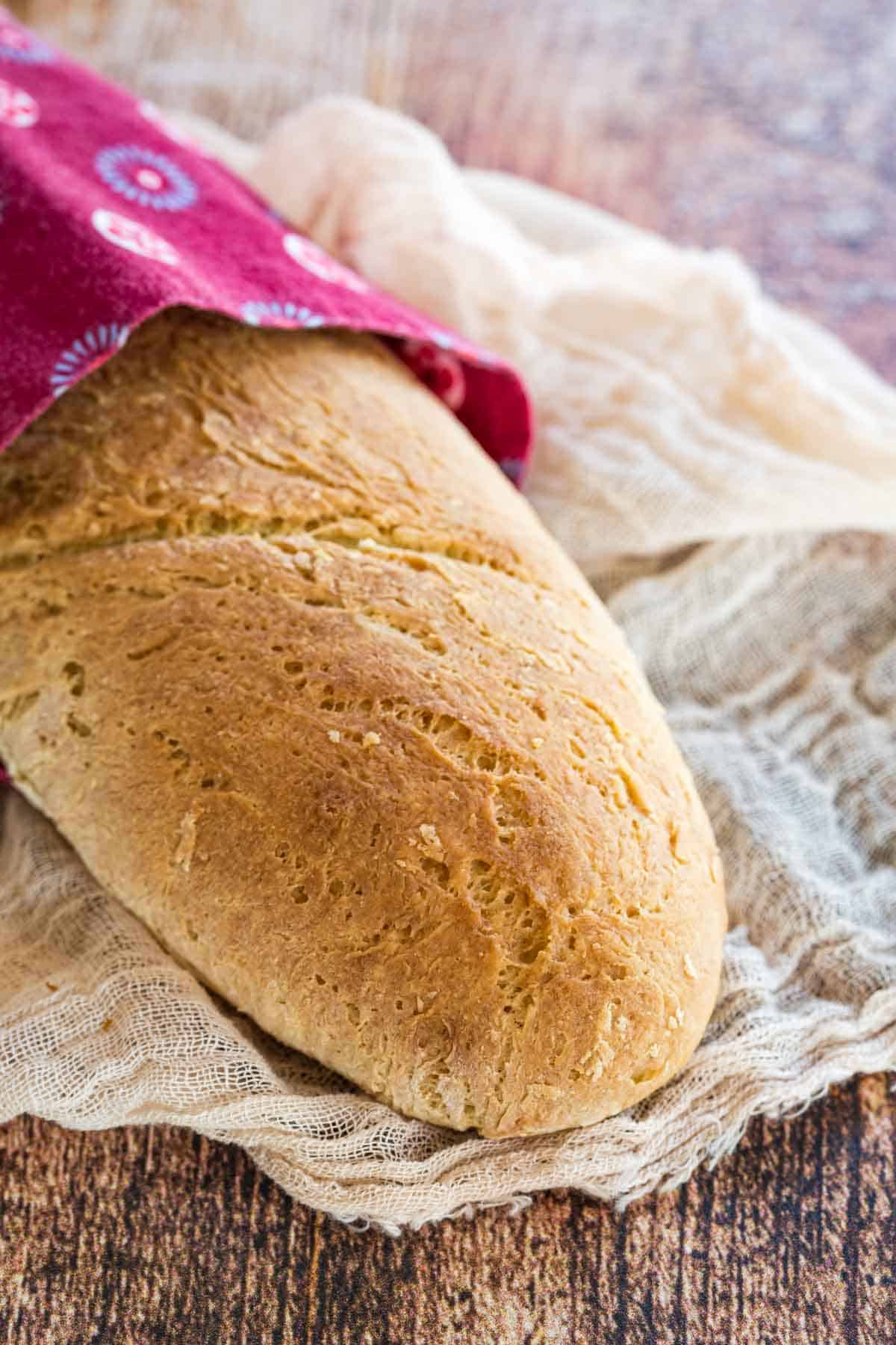 A gluten free French baguette wrapped in a pink cloth.