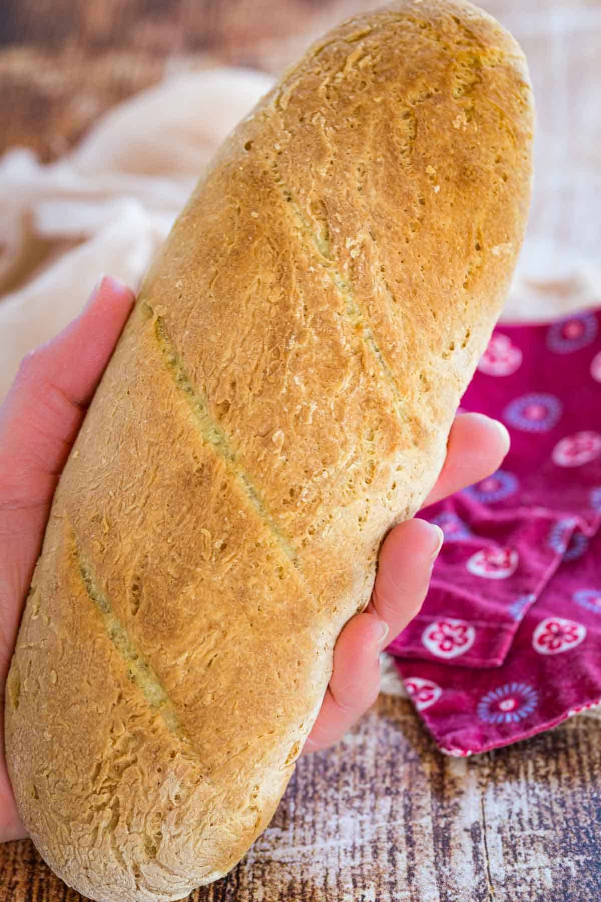 A hand holding a homemade French baguette.