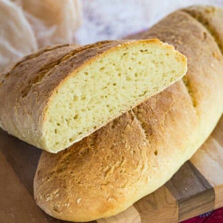 Gluten free French baguettes on a wooden cutting board.