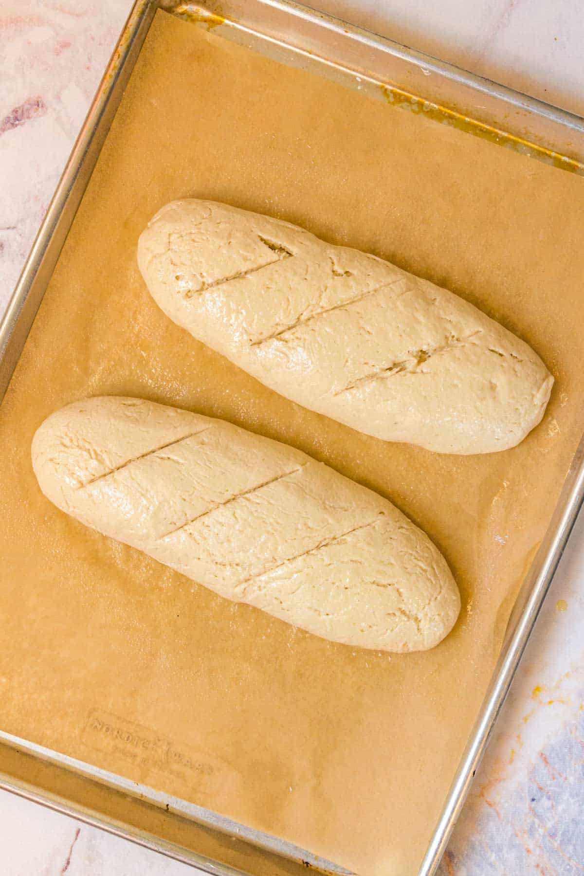 Gluten free baguettes on a baking sheet ready to be baked.