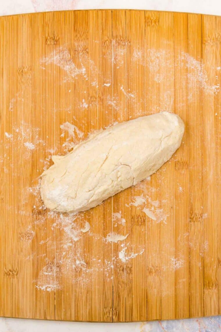 One half of the baguette dough on a wooden work surface.