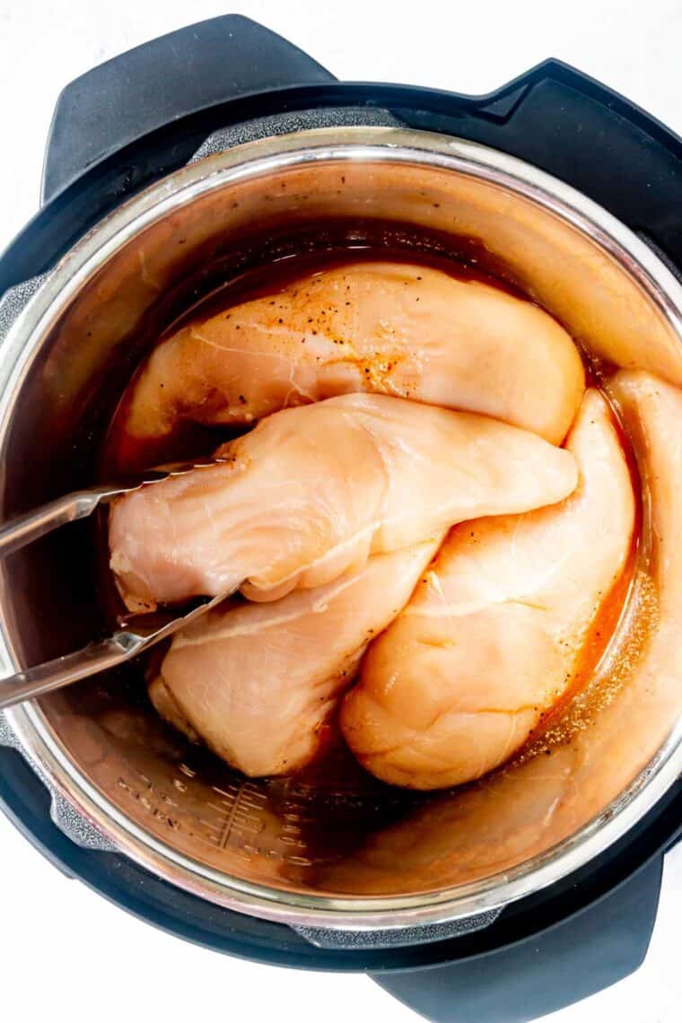 Chicken breasts inside an Instant Pot with seasonings.