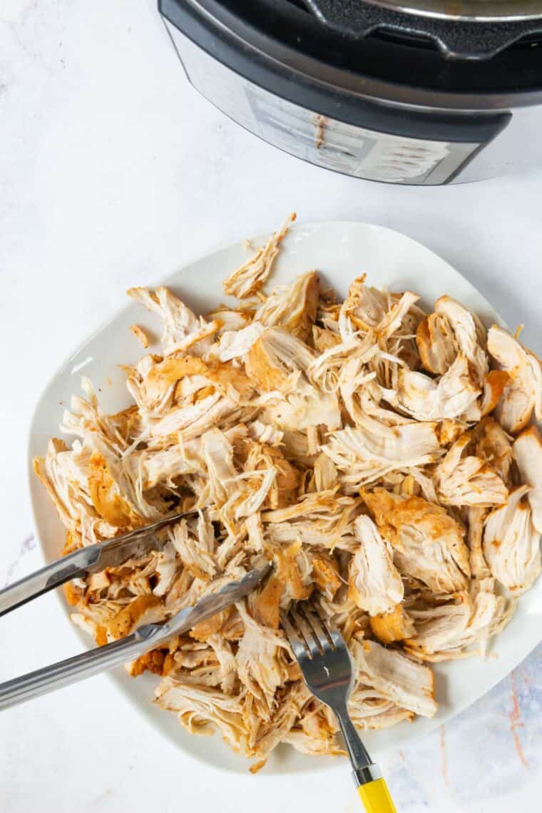 Cooked chicken is shredded on a plate.