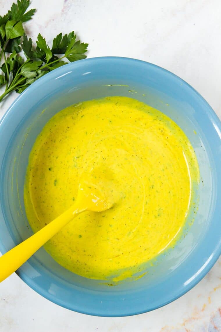 Mustard coleslaw dressing in a blue mixing bowl.