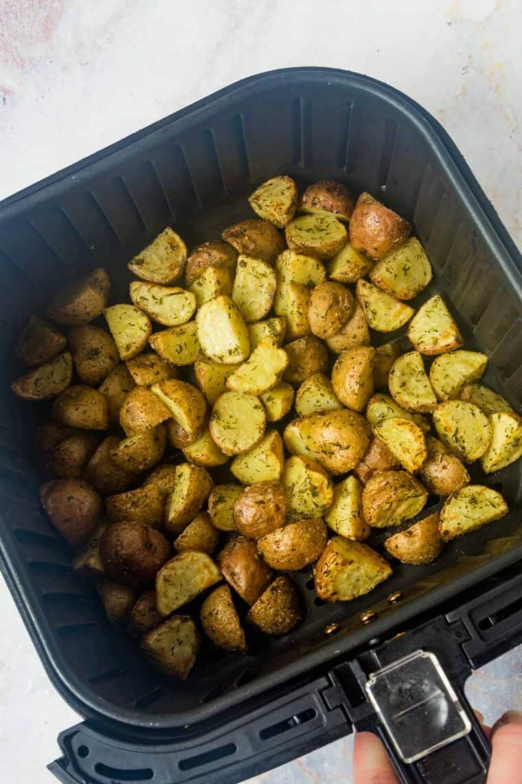 Crispy ranch potatoes in the basket of an air fryer.