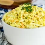Mustard coleslaw in a bowl garnished with parsley.