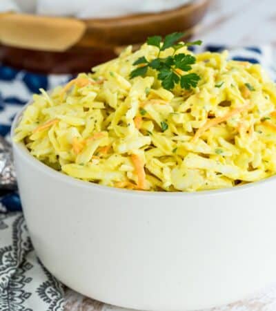Mustard coleslaw in a bowl garnished with parsley.
