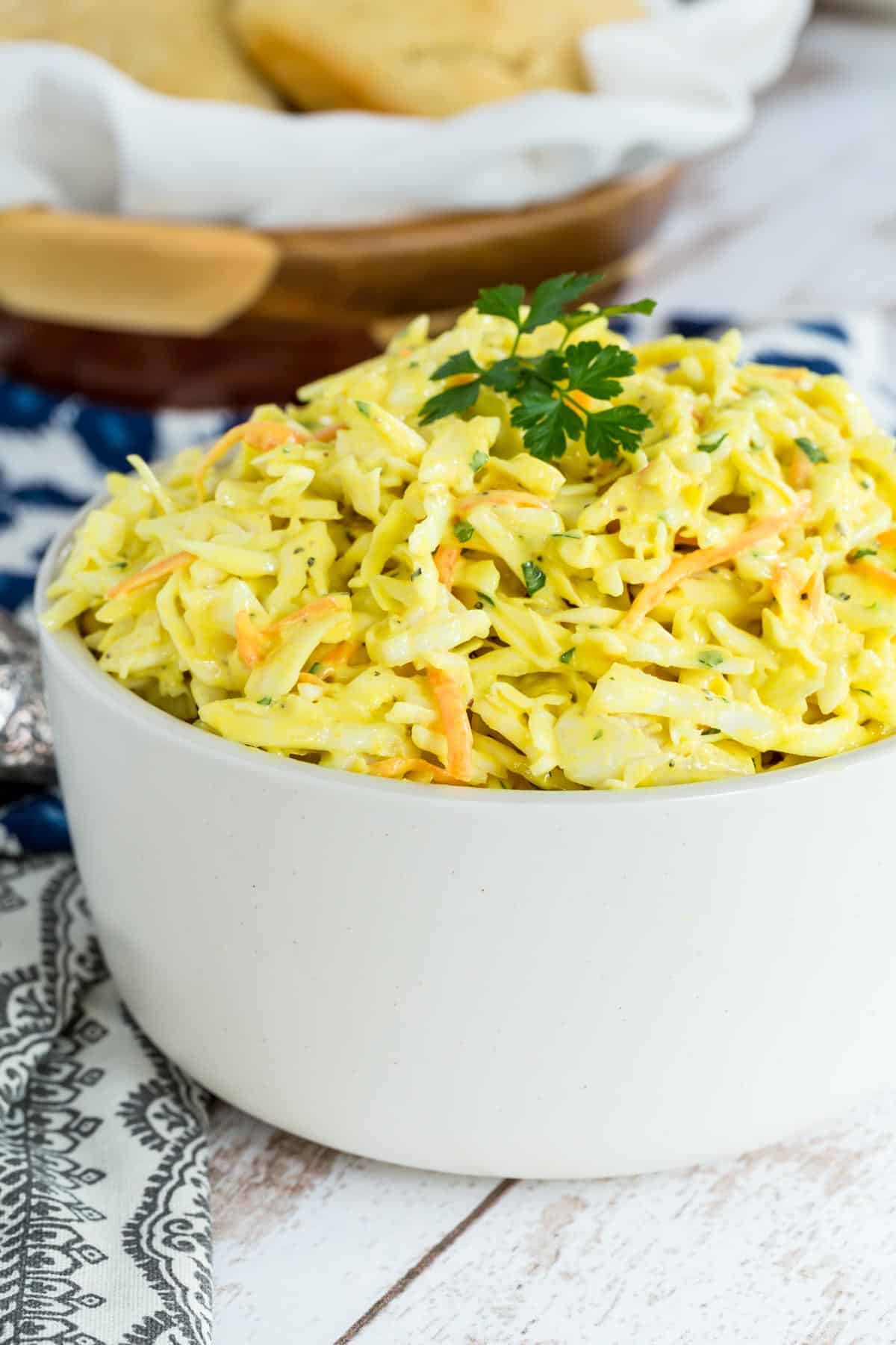 Mustard coleslaw in a bowl garnished with parsley.