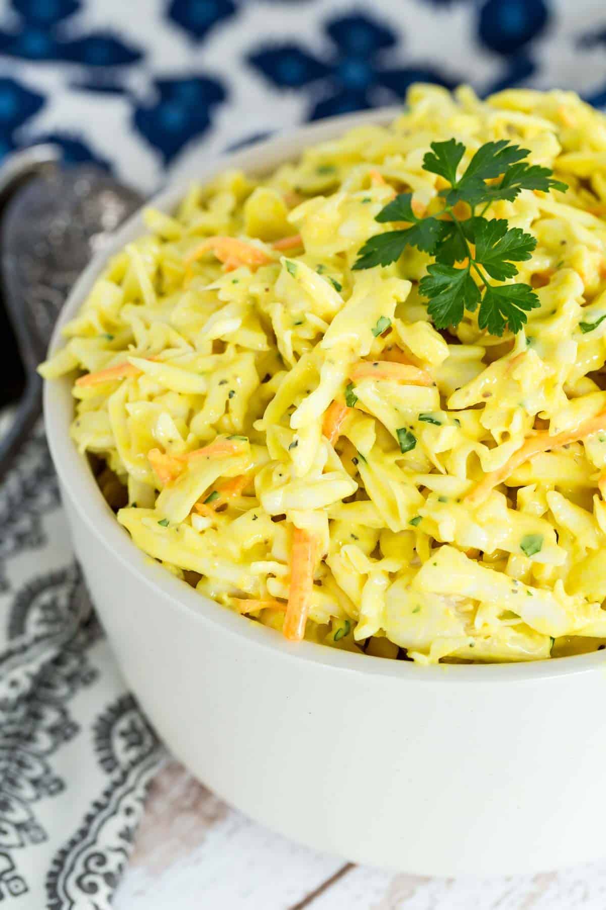 Mustard coleslaw in a bowl garnished with parsley.