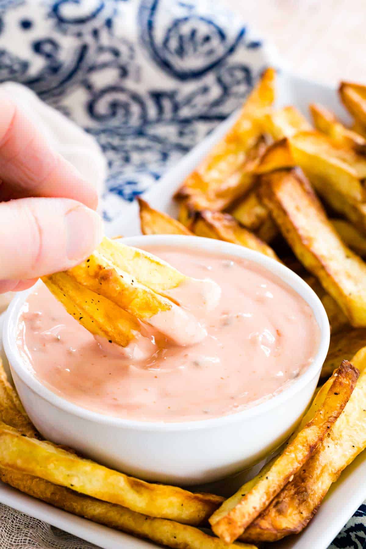 Fingers dipping French fries into a bowl of homemade Big Mac Sauce.