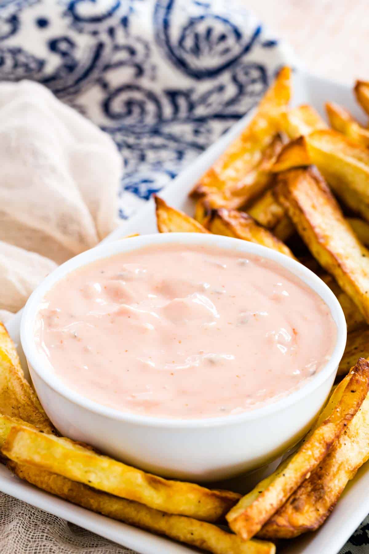 A bowl of healthy Big Mac Sauce on a rectangular plate with French fries.