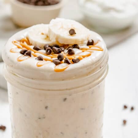 A peanut butter smoothie in a jar topped with banana slices and chocolate chips