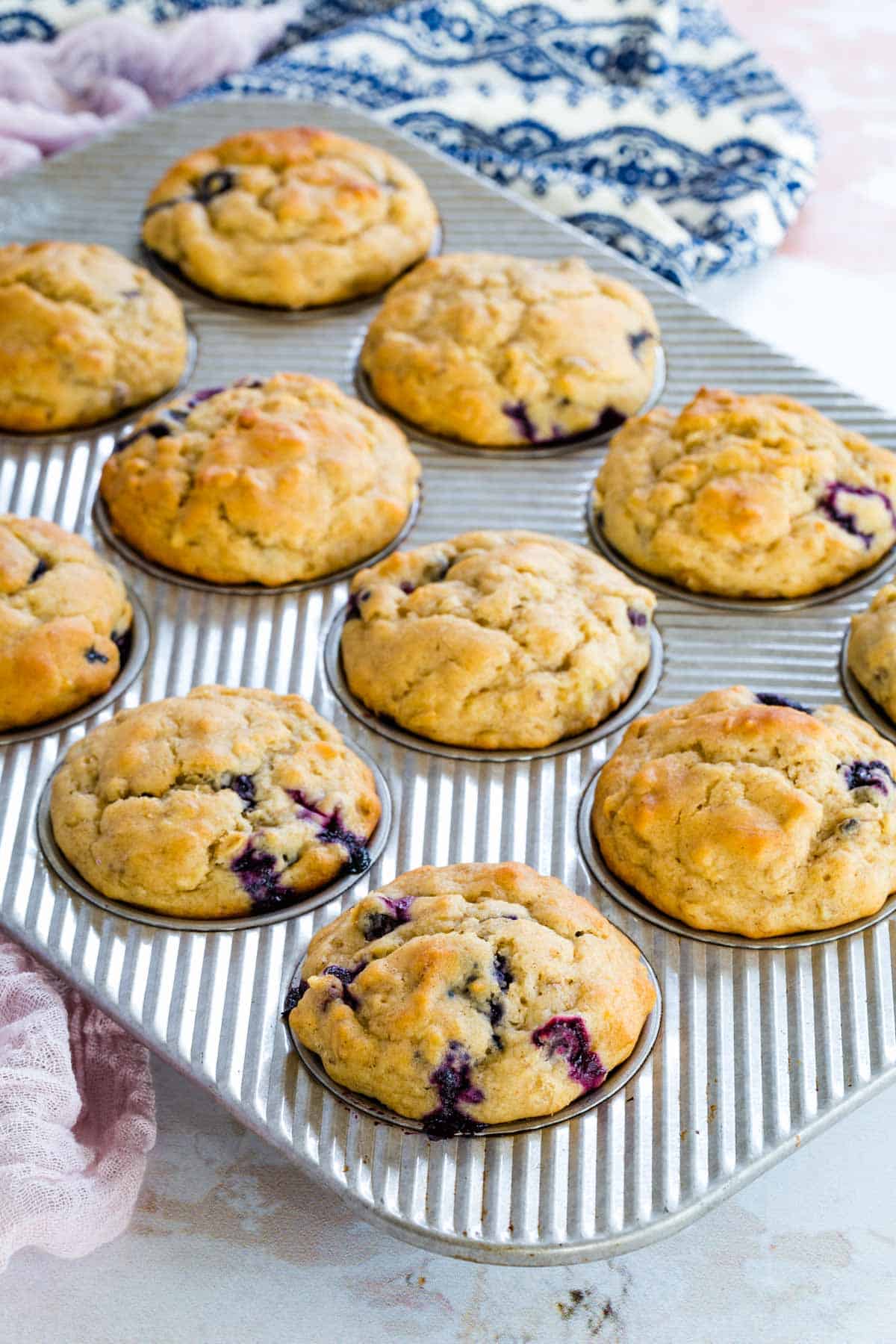 12 banana blueberry muffins inside of a metal muffin tin on a kitchen countertop