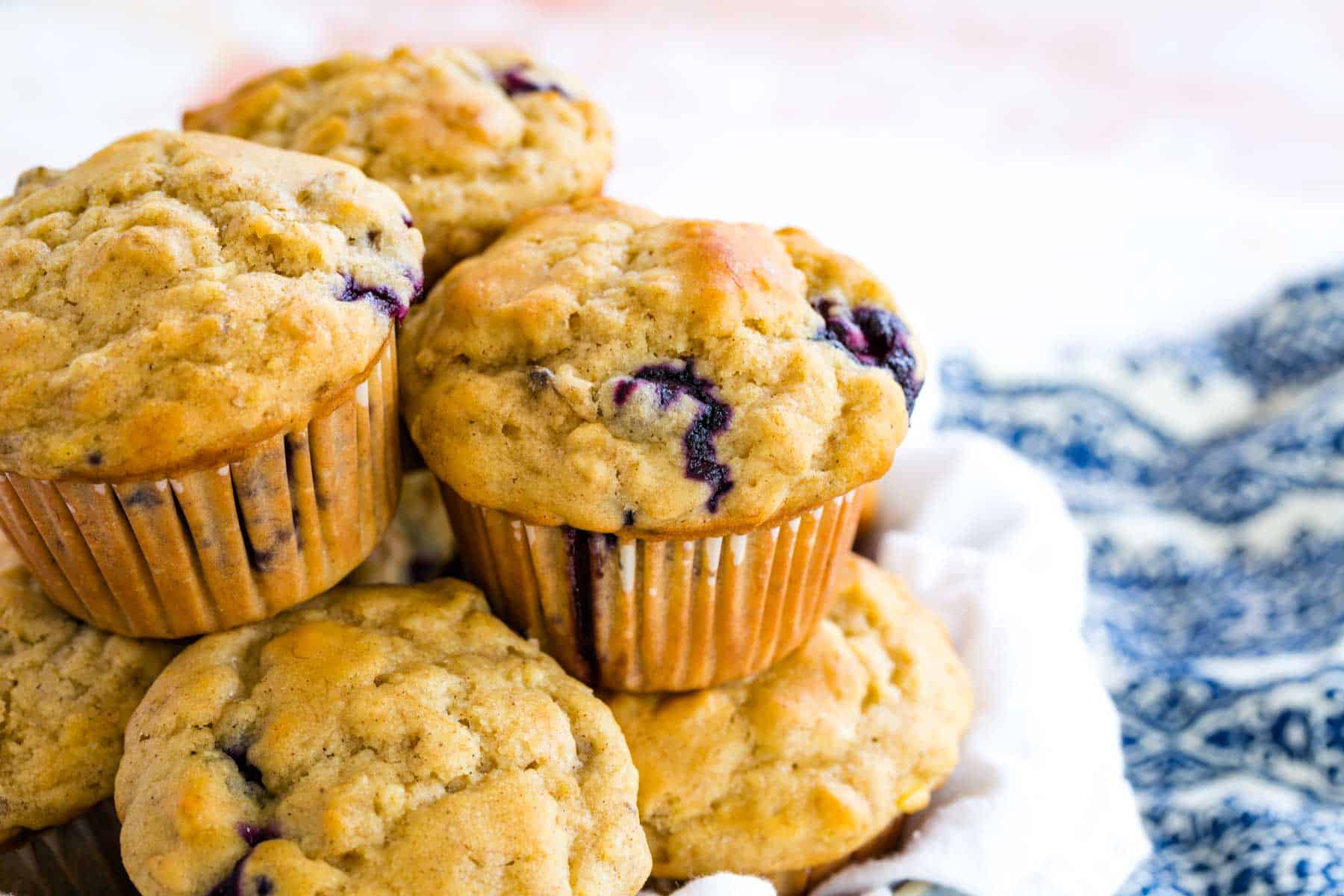 Gluten-free muffins piled into a basket on top of a decorative placemat